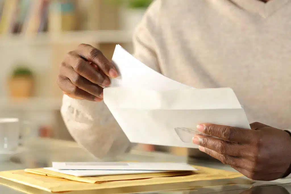 Close up of mans hands opening an envelope, representing the Viking Service Collection Letters settlement.
