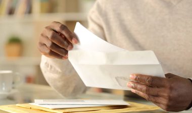 Close up of mans hands opening an envelope, representing the Viking Service Collection Letters settlement.