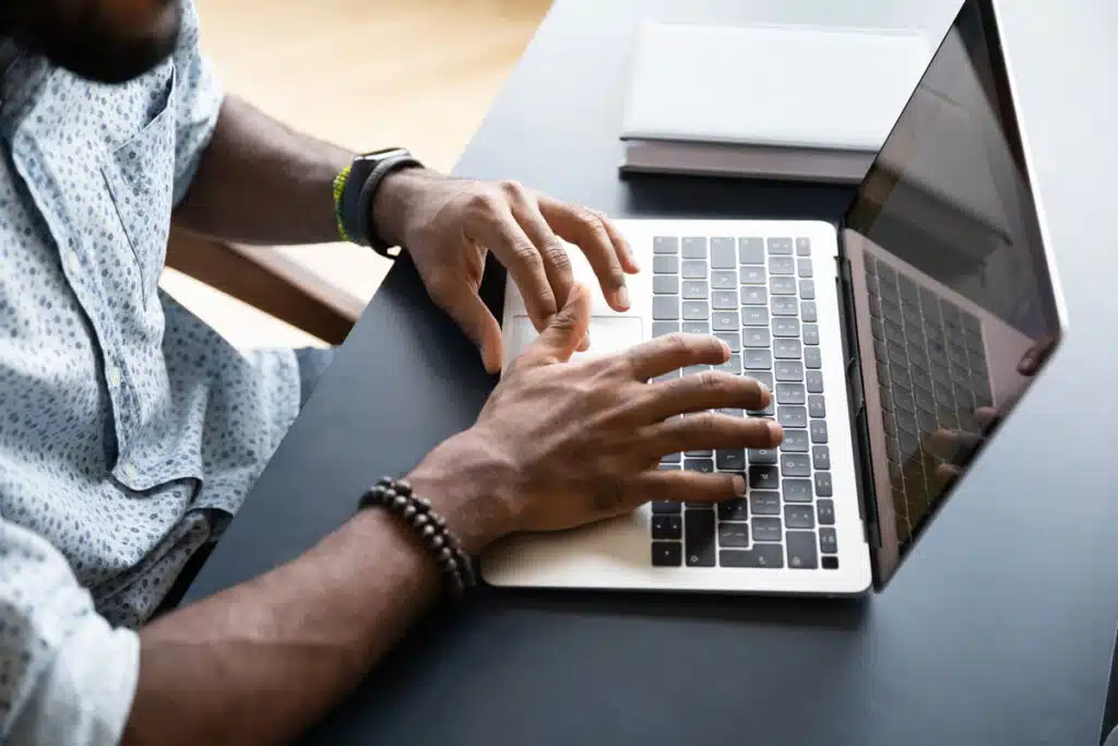 Close up of mans hands typing on a laptop keyboard, representing the Illinois RocketReach privacy class action lawsuit settlement.