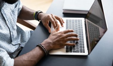 Close up of mans hands typing on a laptop keyboard, representing the RocketReach privacy settlement.