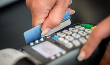 Close up of a person swiping a debit card, representing the Redstone Federal Credit Union fees settlement.