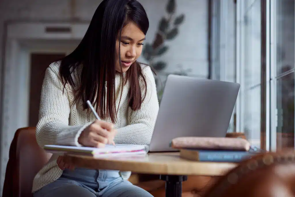 A female student studying with her laptop in a coffee shop, representing the Marymount Manhattan College data breach class action lawsuit settlement.