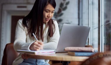 A female student studying with her laptop in a coffee shop, representing the Marymount Manhattan College data breach.