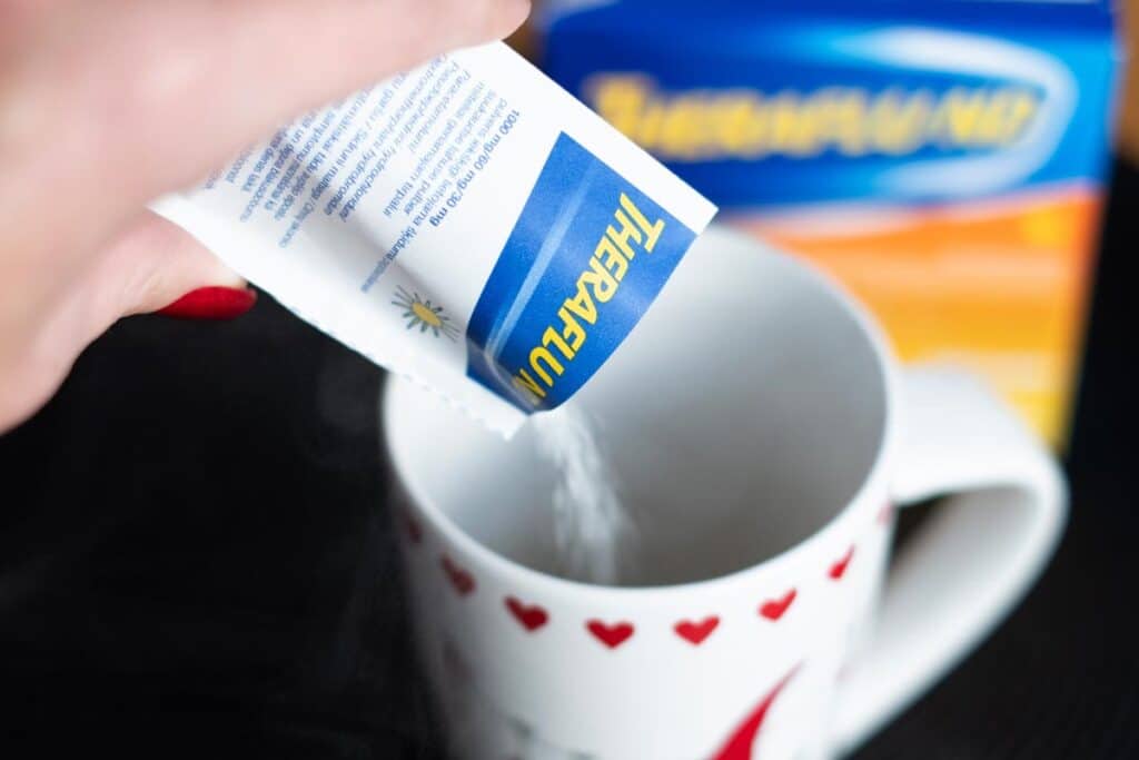 Close up of a hand pouring Theraflu Emergen-C into a mug, representing the Theraflu Emergen-C class action.