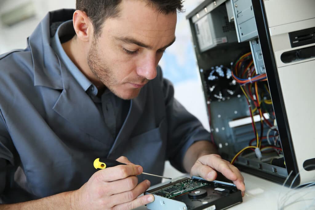 Close up of a computer technician working on a computer, representing the Eight Eleven Group settlement.
