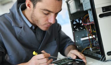 Close up of a computer technician working on a computer, representing the Eight Eleven Group settlement.