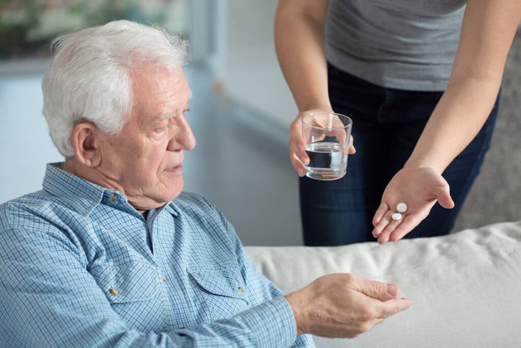 Close up of an elderly man being handed pills.