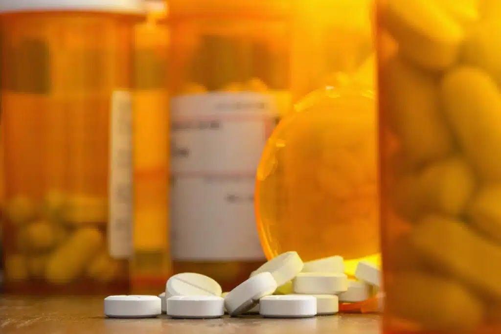 Close up of white painkillers on a table surrounded by prescription bottles, representing the opioid crisis and the New Mexico Walgreens settlement.