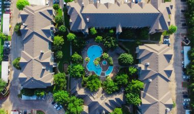 Aerial view of an apartment complex with a pool, representing the Vasona Management settlement.