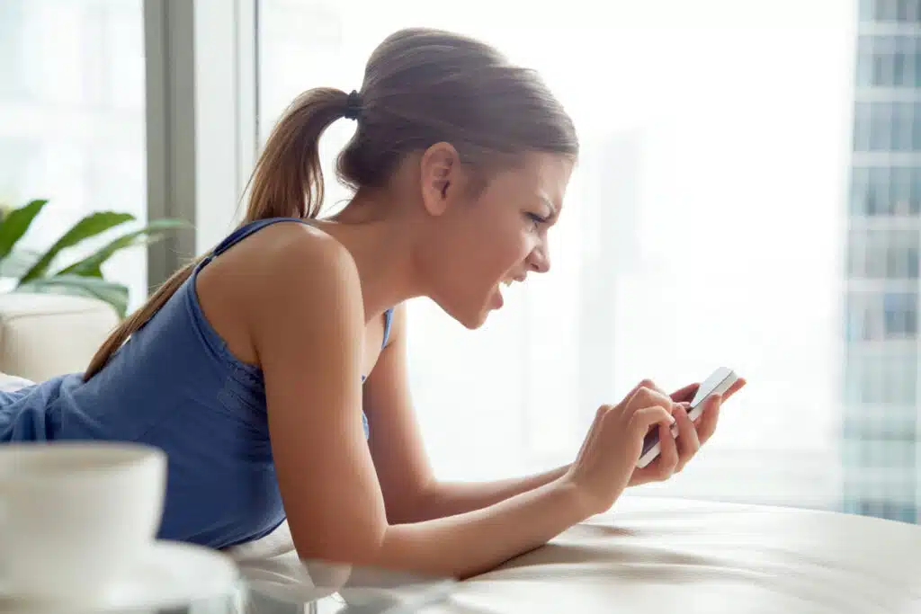 Irritated woman reading a text on her smartphone, representing TCPA class actions.