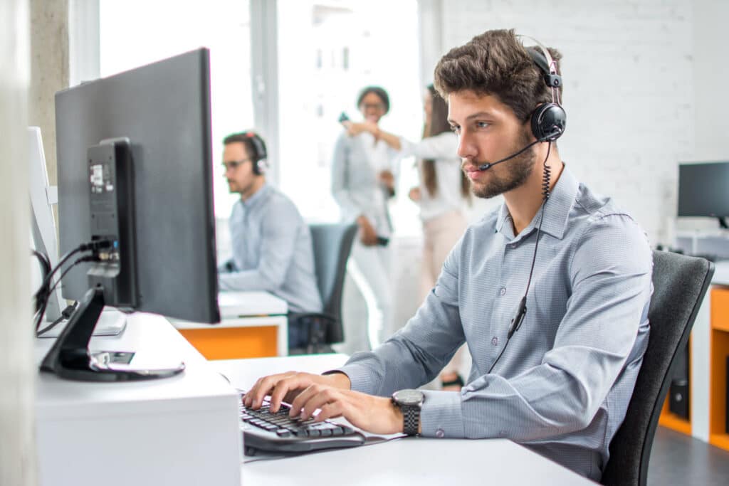 A young customer service worker typing on a computer, representing the Top Flite Financial CIPA settlement.
