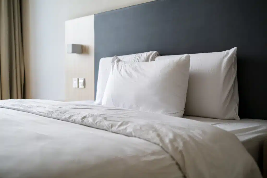 White pillows and bedding on a made bed, representing the Macy's sheets settlement
