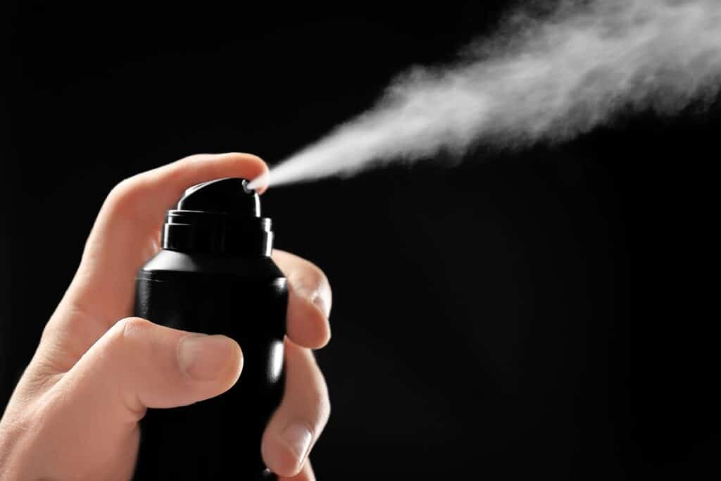 Close-up of a person spraying an aerosol spray against a black background, representing the Right Guard settlement.