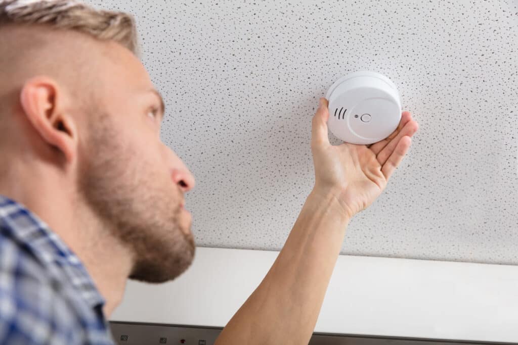 A man changing a smoke detector, representing the Kidde/First Alert class action.