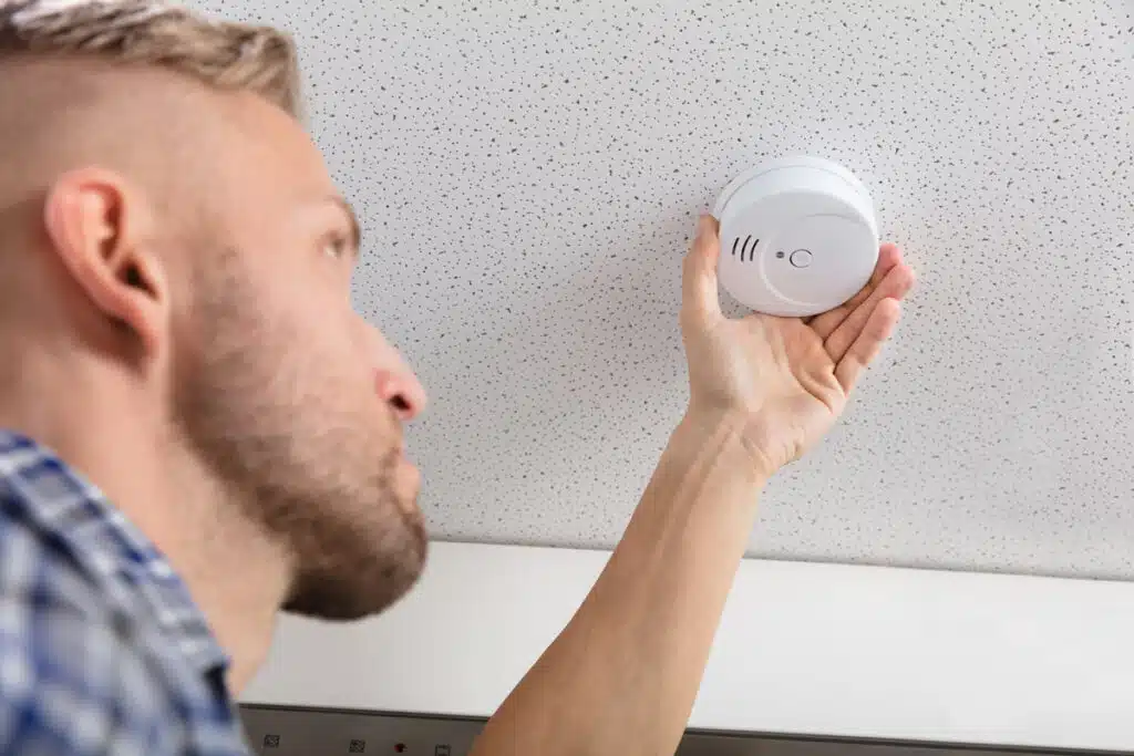 A man changing a smoke detector, representing the Kidde/First Alert class action.