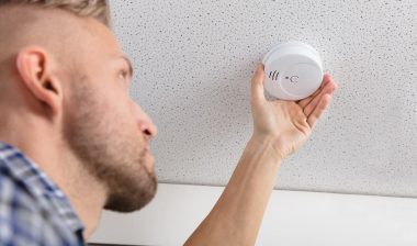 A man changing a smoke detector, representing the Kidde/First Alert class action.
