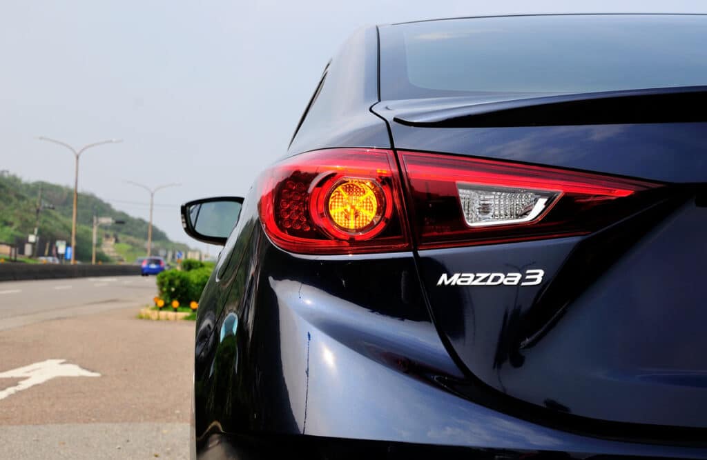 Mazda3 emblem on bumper of vehicle, representing the Mazda rearview mirror defect recall.