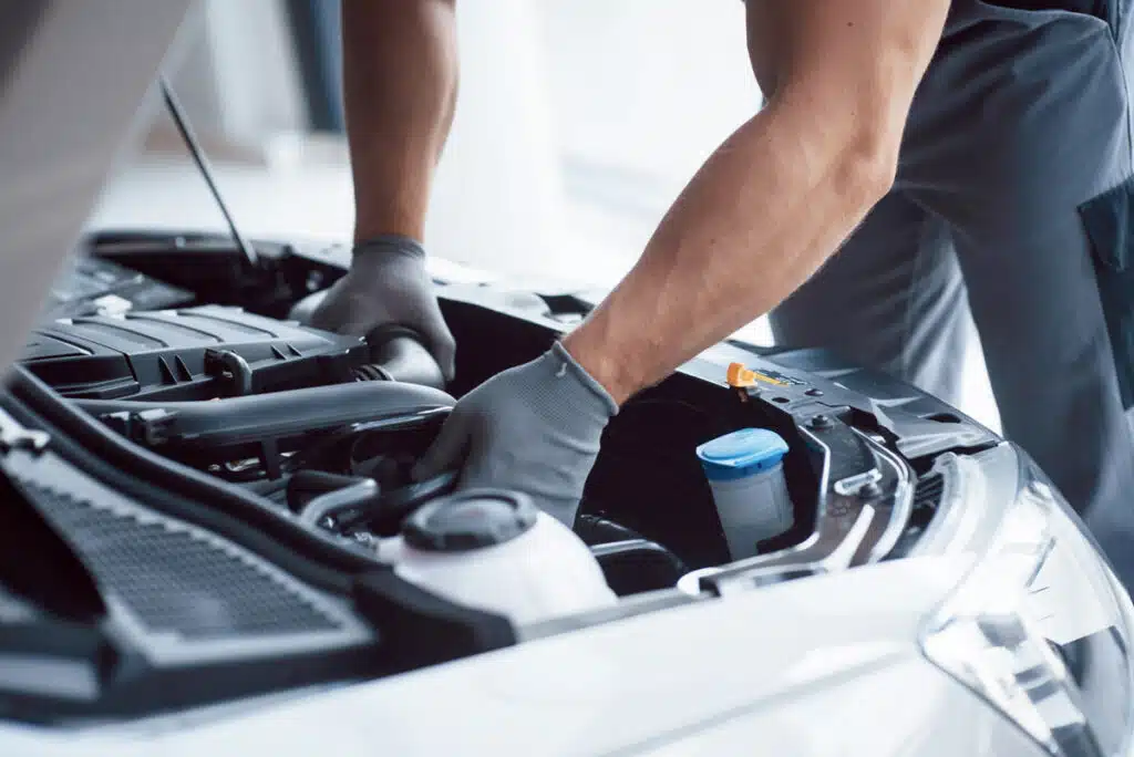 Close up of a mechanic fixing a car engine, representing vehicle recalls.