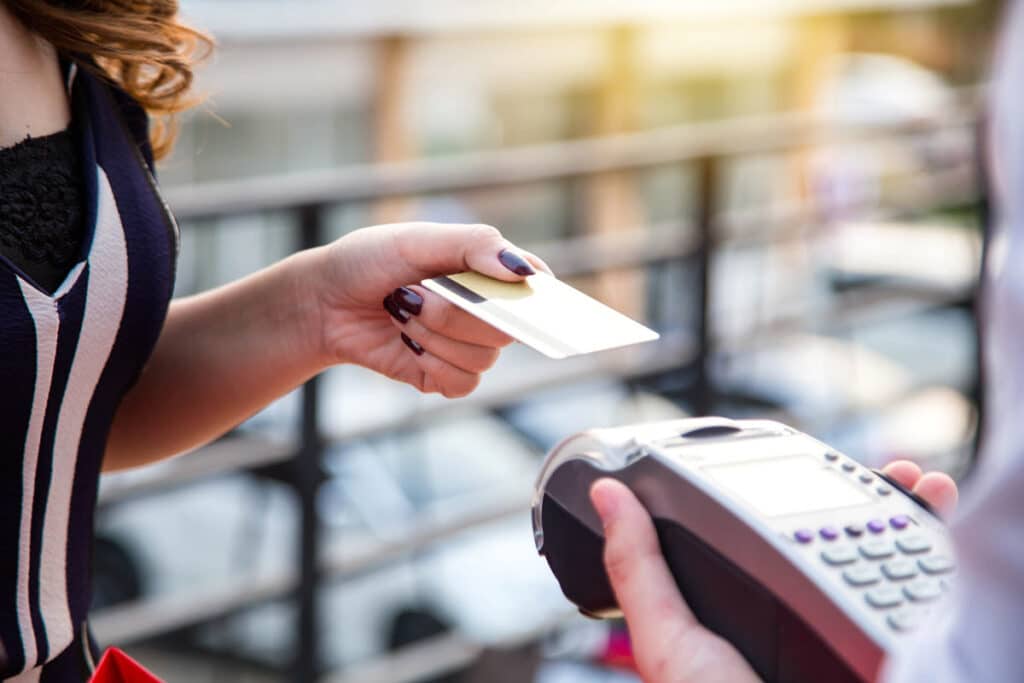 Close up of a woman using a card on a point-of-sale machine, representing the Desert Financial Credit Union overdraft fees class action lawsuit settlement.