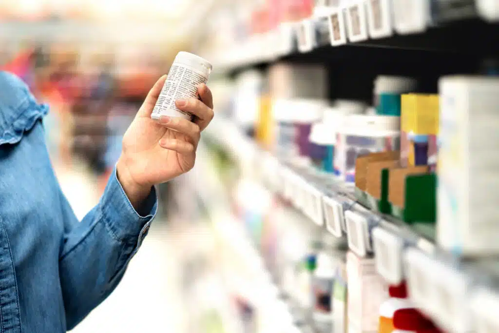 Close up of a customer holding a medicine bottle inside a store, representing recent medication lawsuits.