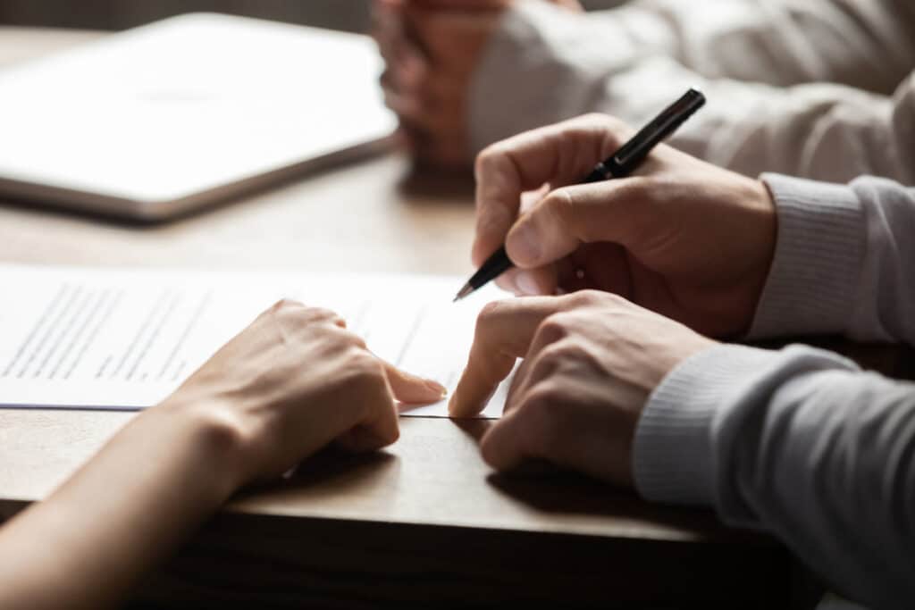 Close up of a person filling out paperwork, representing the Lohman Property Management fees class action lawsuit settlement.