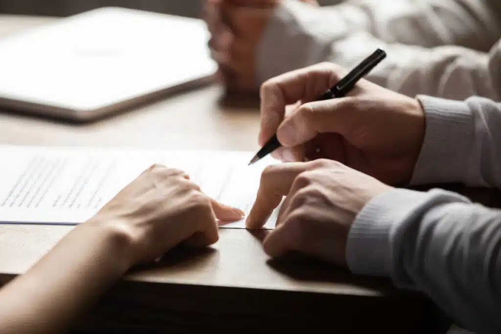 Close up of a person filling out paperwork, representing the Lohman Property Management fees class action lawsuit settlement.