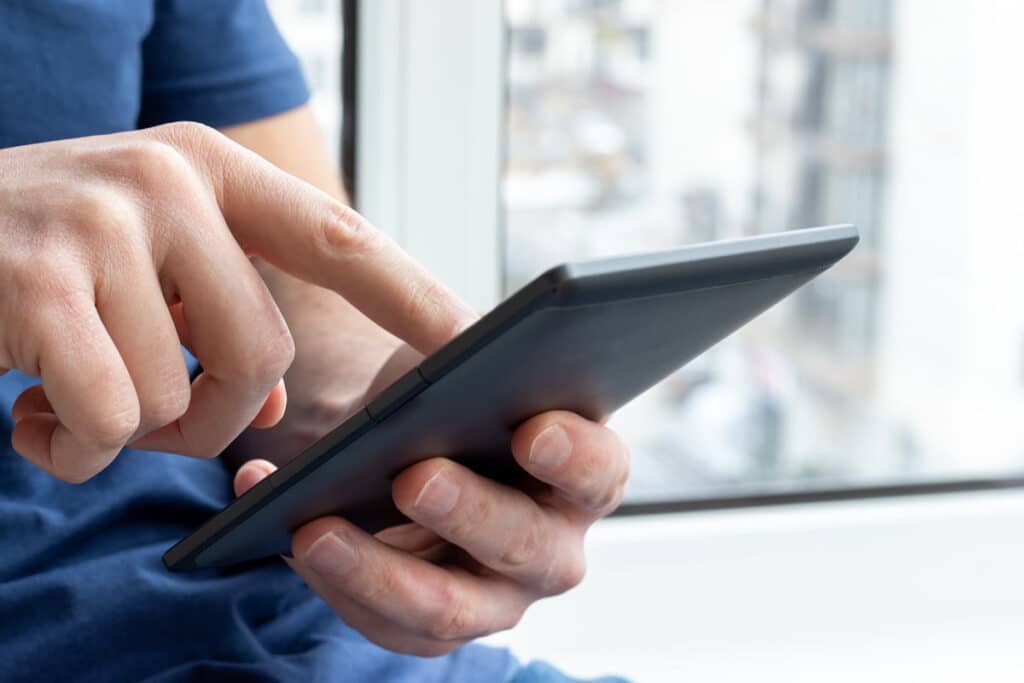Close up of mans hand touching a screen, representing the DOJ proposed rules for website accessibility.