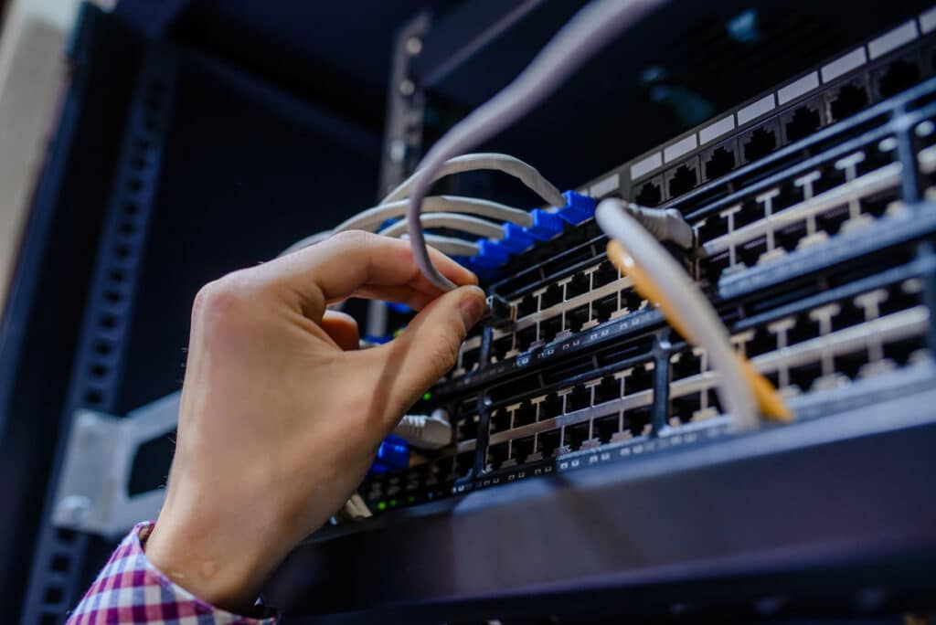 Close up of a technician adjusting network cables, representing the Citywide Home Loans data breach settlement.