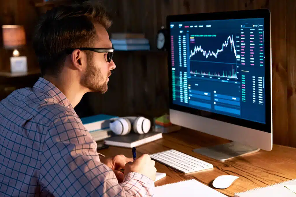 A man looking at a cryptocurrency graph on his computer, representing crypto exchanges.