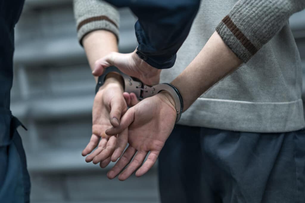 Close up of handcuffs on a mans hands, representing the crypto hack.