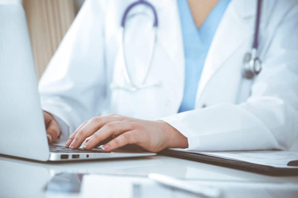 Close up of a doctor typing on a laptop, representing the HCA Healthcare data breach class action.