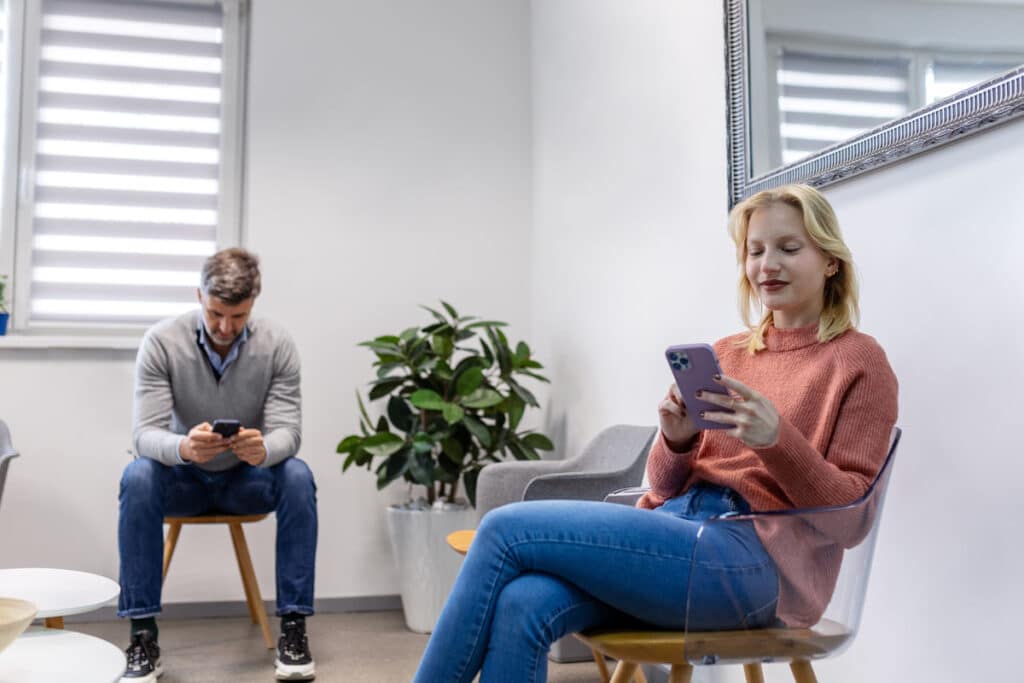 People using their smartphones in a waiting room, representing the Froedtert Health class action lawsuit settlement.