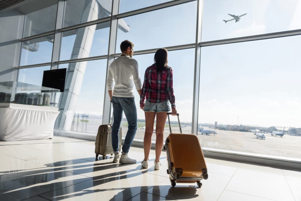 A young couple in an airport watching a plane take off, representing the American Airlines lawsuit.