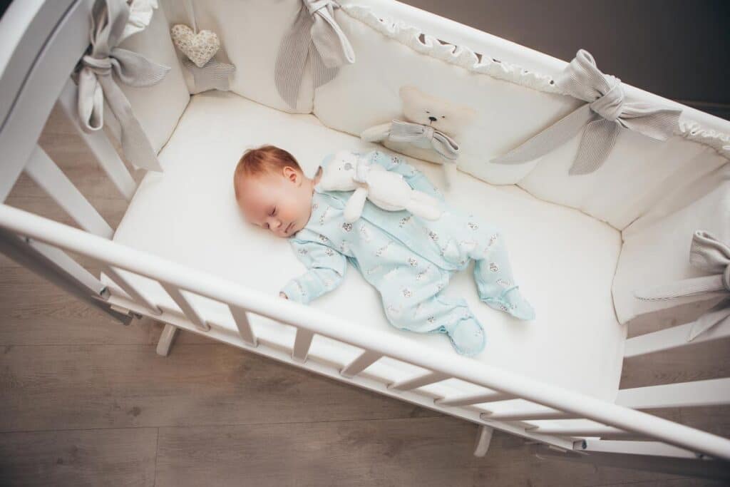 Baby sleeping in a crib, representing the inclined sleeper and crib bumper rules.