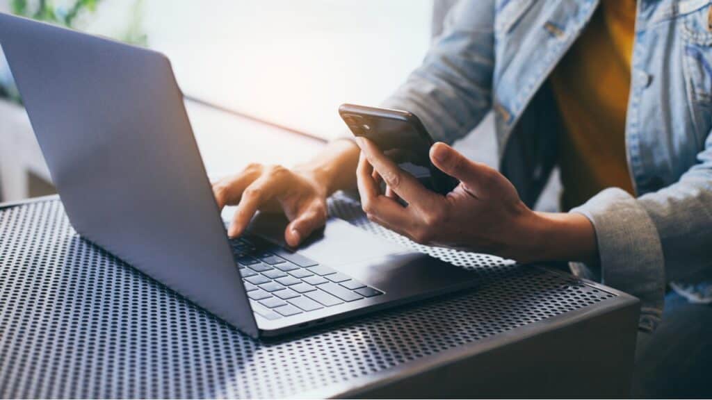 A man uses a laptop and cellphone, representing the ClassPass class action lawsuit settlement.