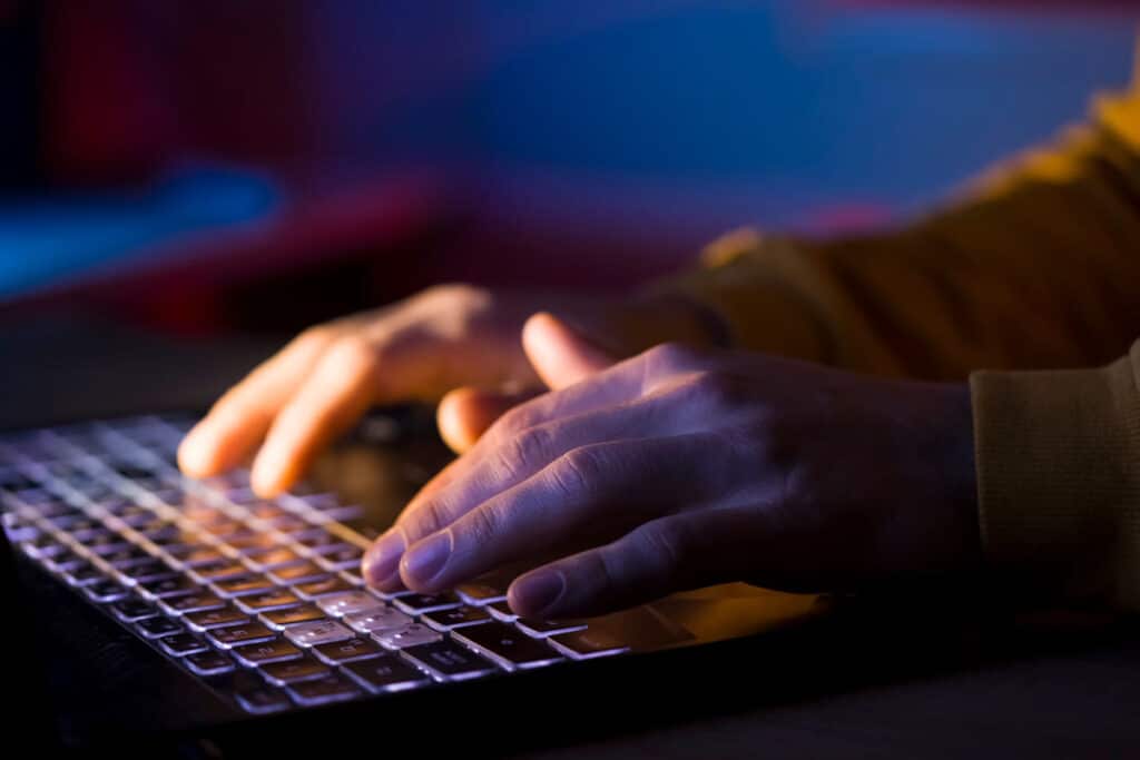 Close up of a mans hands typing on a laptop, representing the Creative Ventures Pro Wrestling Tees class action lawsuit settlement.