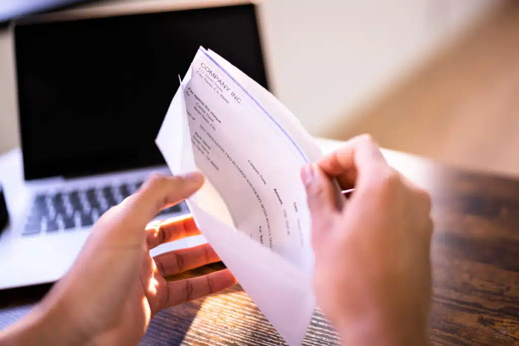 Close up of a person opening an envelope with a check inside, representing the 1st Auto & Casualty Insurance class action lawsuit settlement.