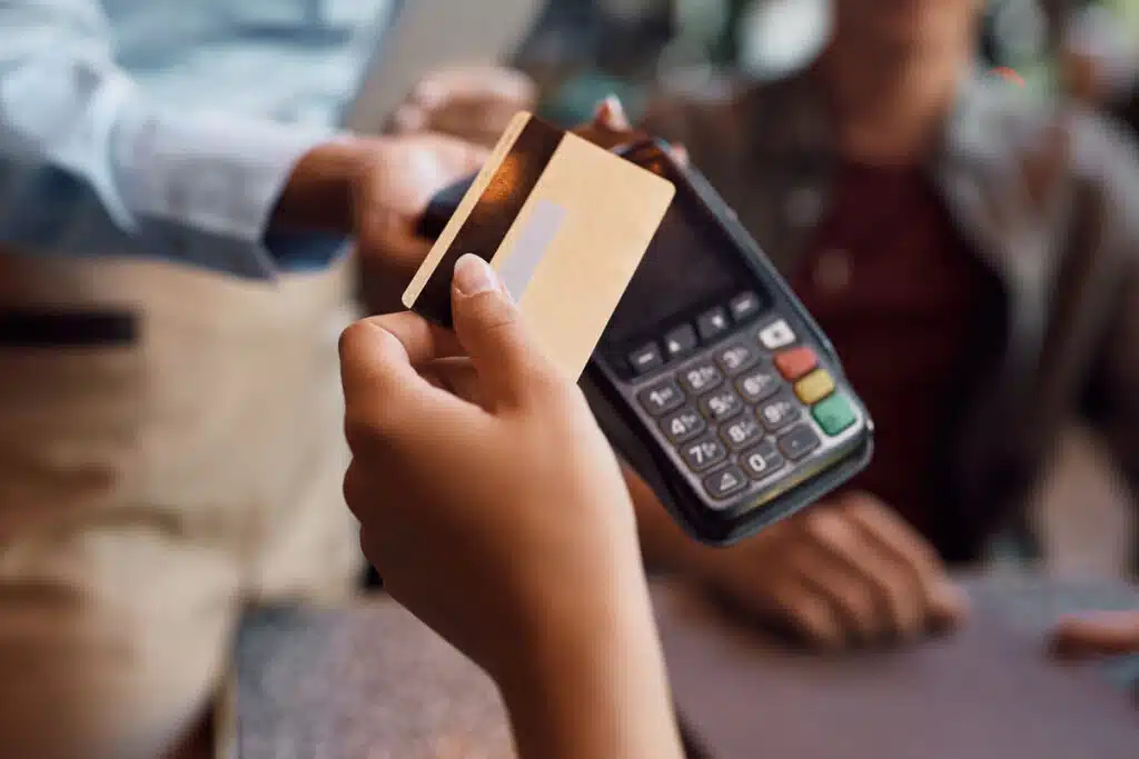 Close up of a debit card being used on a point of sale system, representing the bank class action lawsuits.