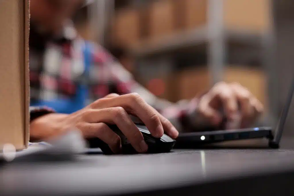 Close up of a males hand using a computer mouse, representing the Bombas website class action.