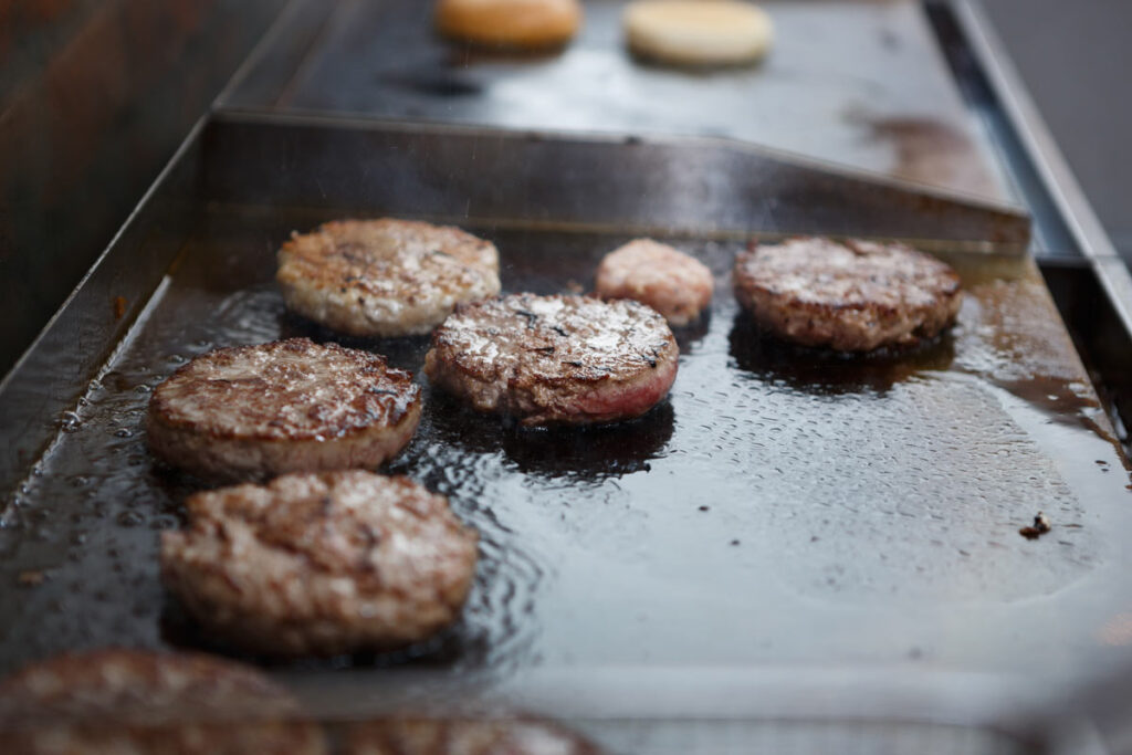 Close up of burger patties being cooked on grill, representing the MrBeast lawsuit.