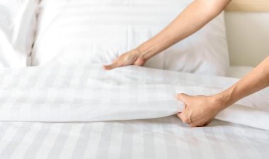 Hand set up white bed sheet in room