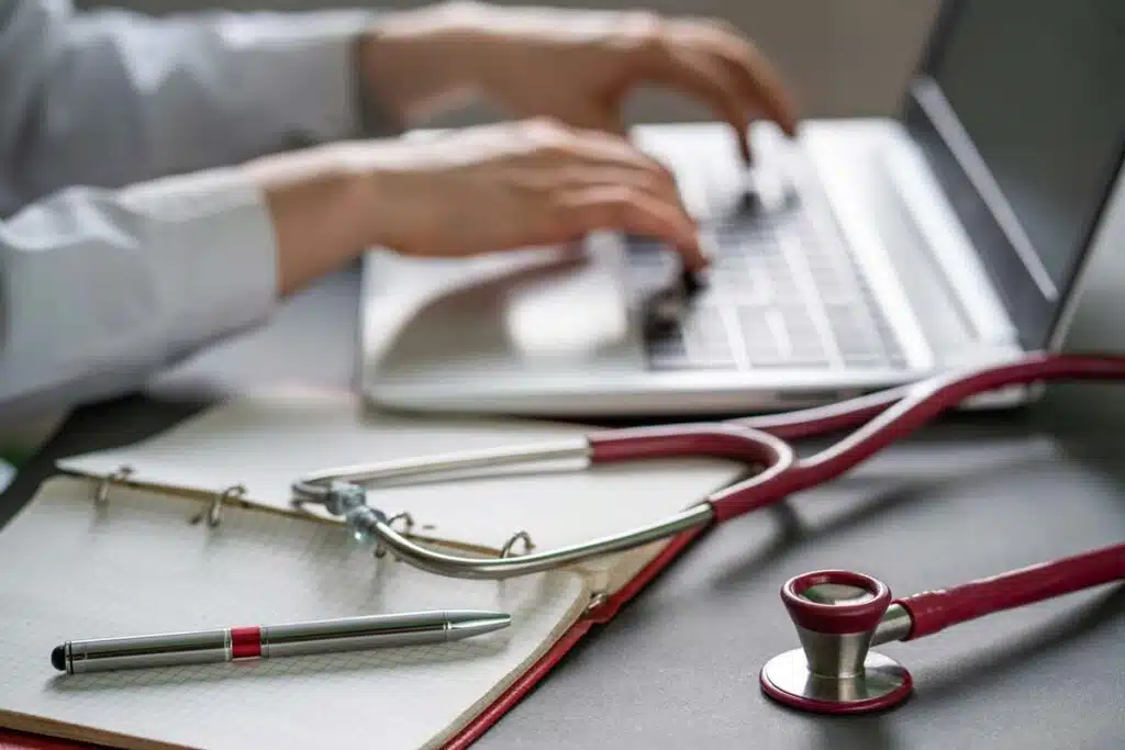 Close up of a doctors hands typing on a laptop, representing the East Tennessee Children's Hospital (ETCH) data breach settlement.