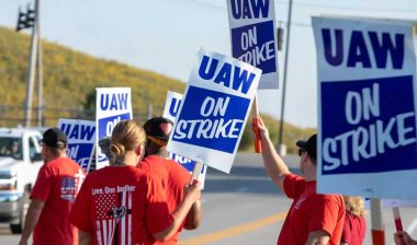 People on strike holding UAW signs, representing the UAW strike.