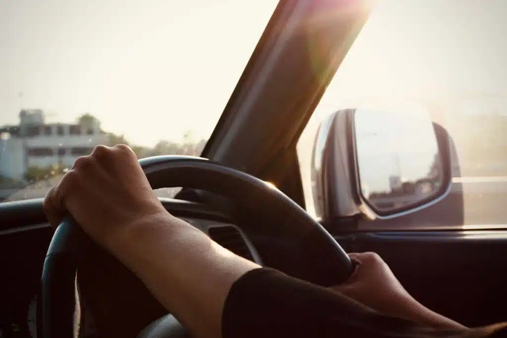 Close up of a womans hands on a steering wheel, representing vehicle recalls in August.