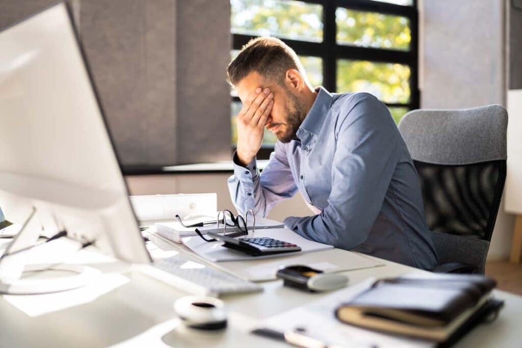 A male worker stressed while working in an office, representing the employee happiness survey.