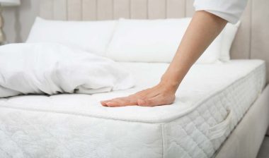 Close up of a womans hand touching a mattress, representing the mattress investigation.