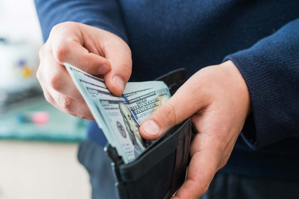 Close up of cash being pulled out of a wallet, representing recent class action rebates.