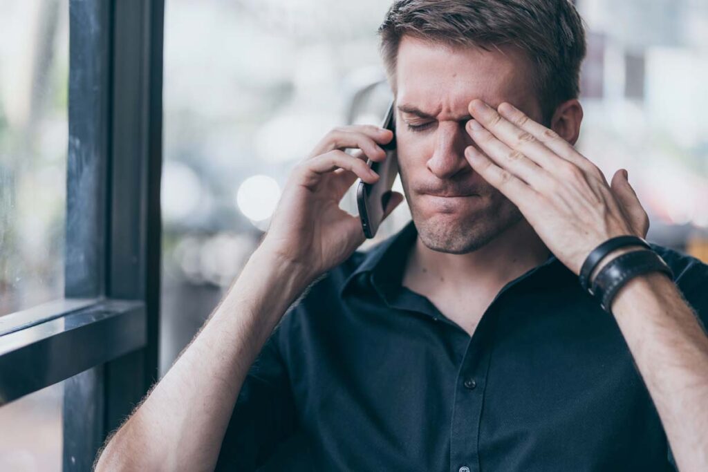 A frustrated man talking on the phone, representing the Aegis Financial settlement.