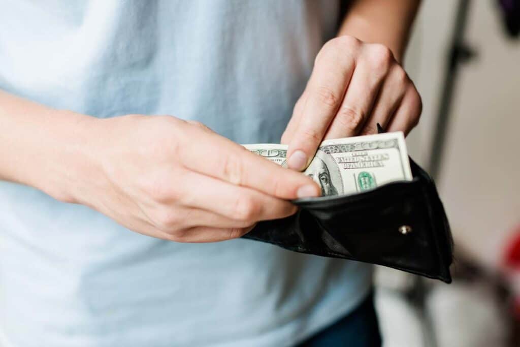 Close up of a mans hands pulling cash from his wallet, representing the citizenship renouncement class action.