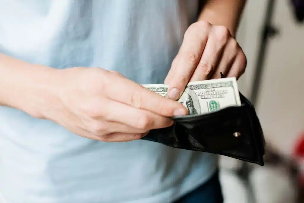 Close up of a mans hands pulling cash from his wallet, representing the citizenship renouncement class action.